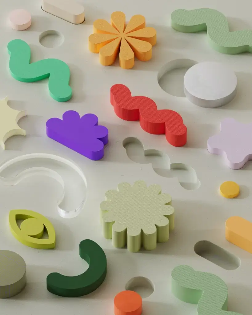 Different coloured shapes on a board with shallow holes cut out.